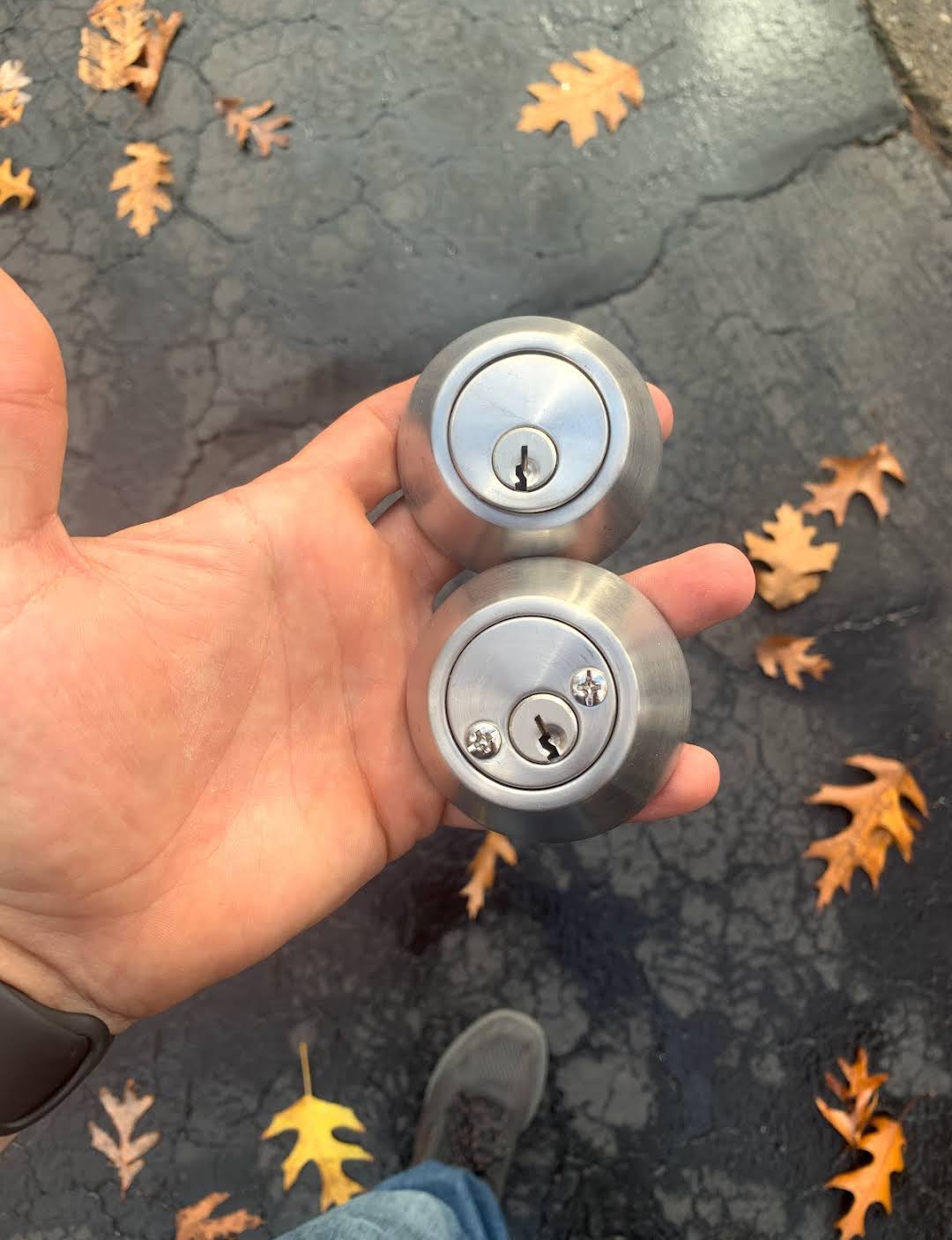 Two rekeyed deadbolt cylinders held in hand after a home rekey service