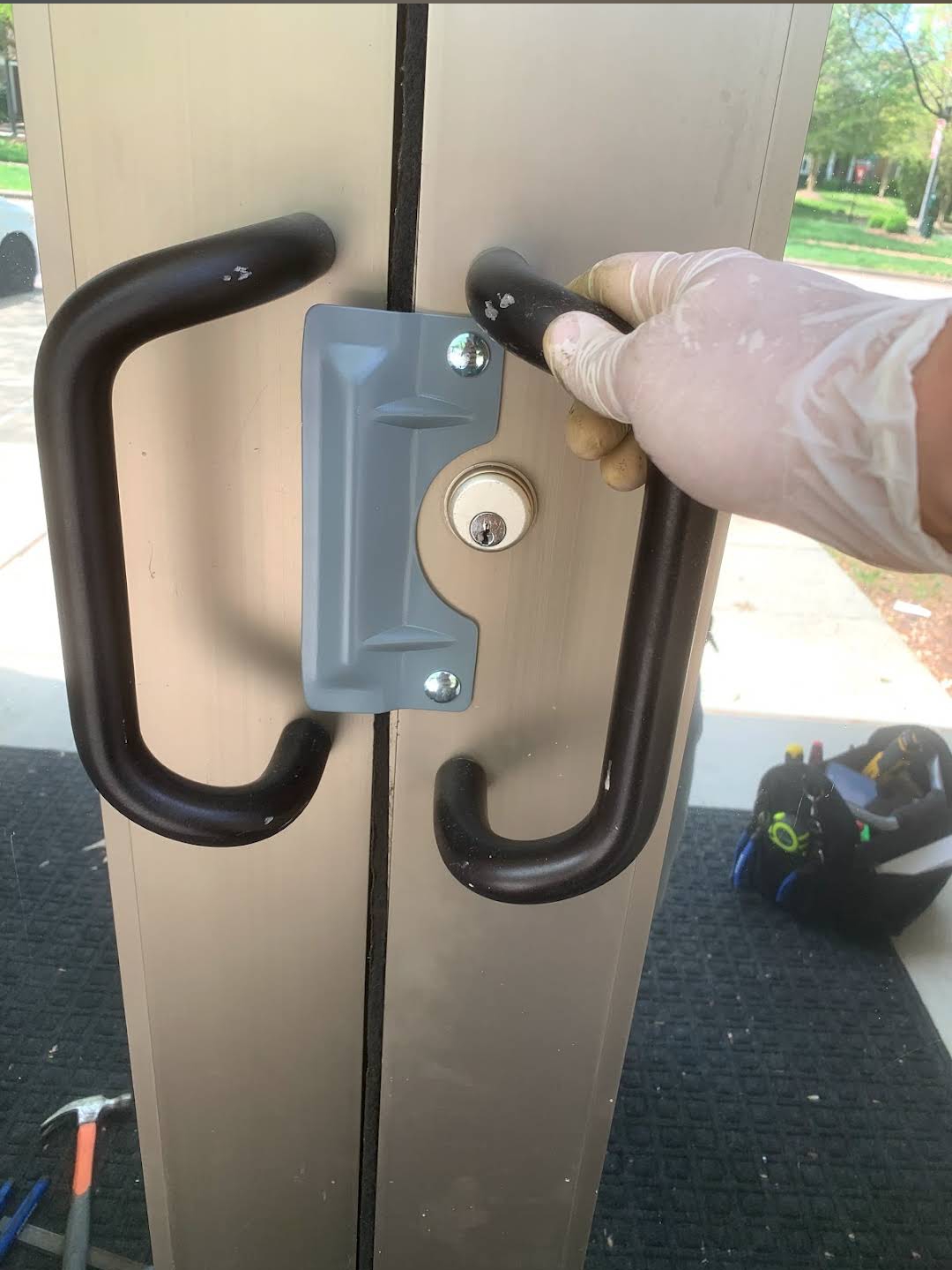 Locksmith repairing a commercial aluminum storefront glass door lock